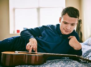 Steven, living with LGS, playing a guitar. Watch his EPIDIOLEX® (cannabidiol) story.